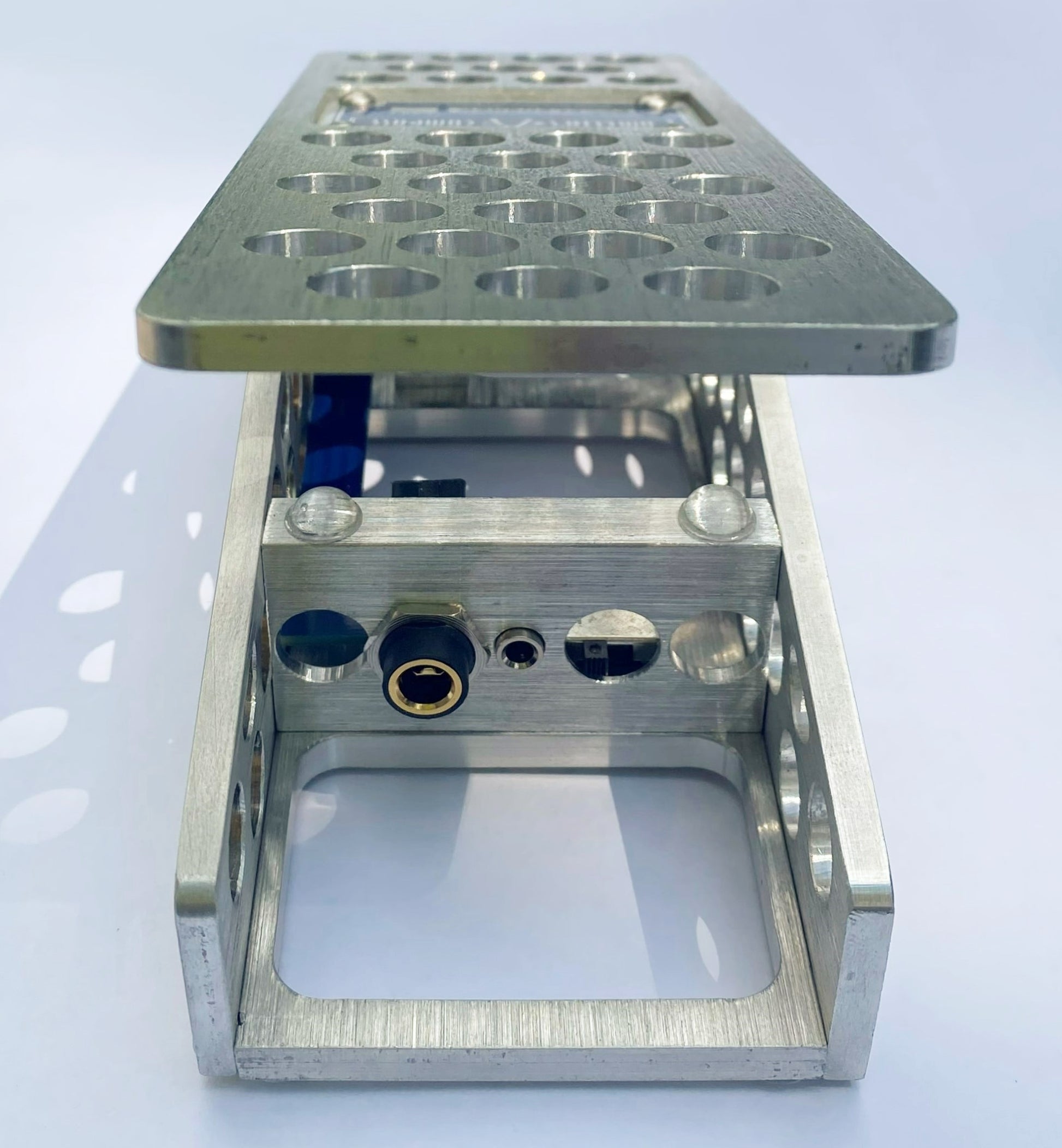 An aluminum PedalPusher expression pedal, featuring multiple holes on the top surface and a blue label in the center.