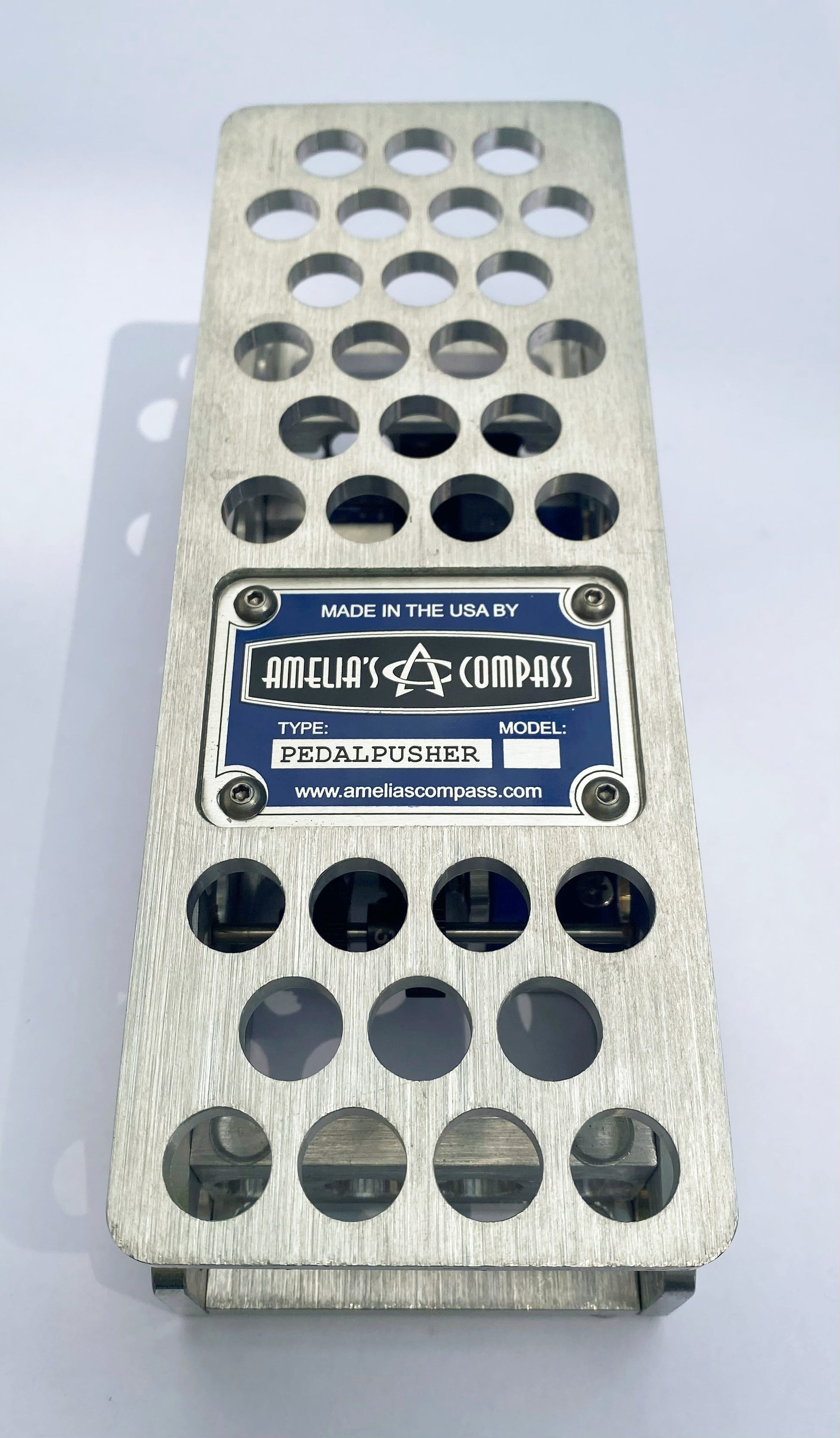 An aluminum PedalPusher expression pedal, featuring multiple holes on the top surface and a blue label in the center.